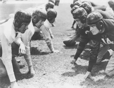 Oyuncular sahada Amerikan futbolu oynarken pozisyon alıyorlar 