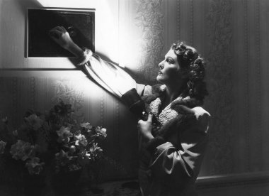 Evinde karanlıkta el feneriyle dolap açan genç bir kadın.  