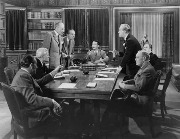 Команда деловых коллег-мужчин спорит друг с другом во время конференции, сидя за столом в офисе 