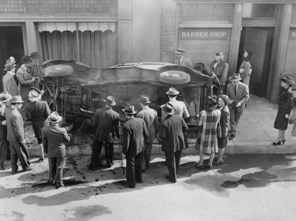 Прохожие смотрят перевернутую машину на тротуаре парикмахерской  