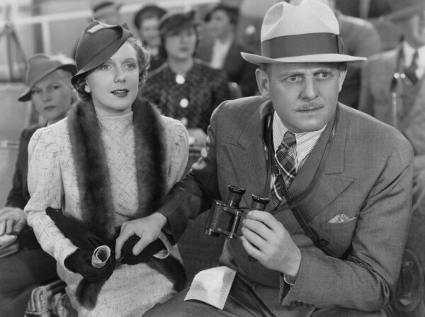 Сосредоточенный взрослый мужчина держит бинокль, сидя с женщиной 