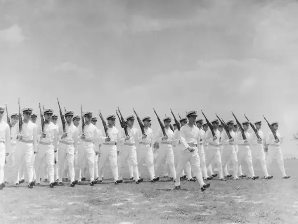 Naval commander leads a group of marching soldiers carrying rifles