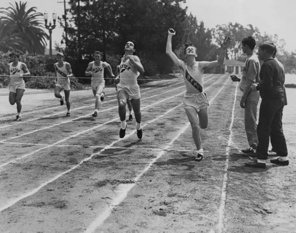 在阳光灿烂的日子里 年轻的男子运动员在跑道上奔跑 免版税图库照片