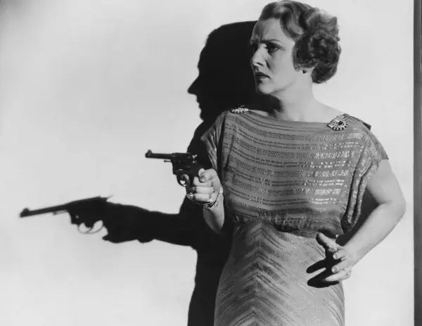 壁に向かって立っている間に銃を目指す怖い女性 — ストック写真