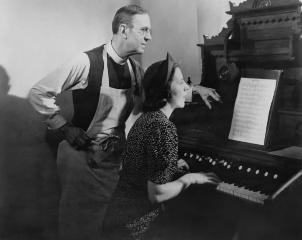 Hombre Ayudando Mujer Mirando Notas Musicales Mientras Aprende Piano Imagen de stock