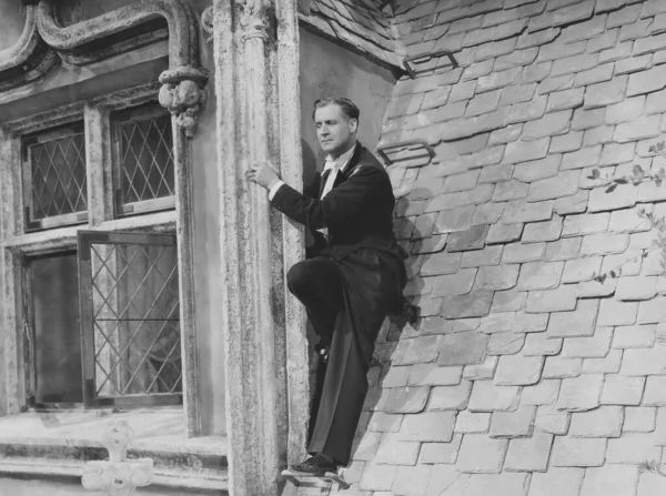一个成熟的男人靠在楼顶的窗户上 图库图片