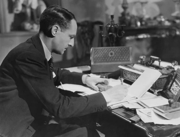 Geschäftsmann Schreibt Tagebuch Während Schreibtisch Sitzt lizenzfreie Stockfotos