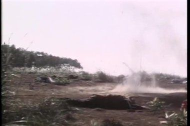 Geniş açılı Asyalı savaşçı patlayıcılarla vurulmamak için takla atıyor.