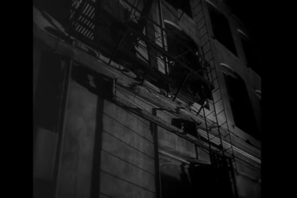 Achteraanzicht Van Mens Die Nachts Brandtrap Naar Beneden Klimt — Stockvideo