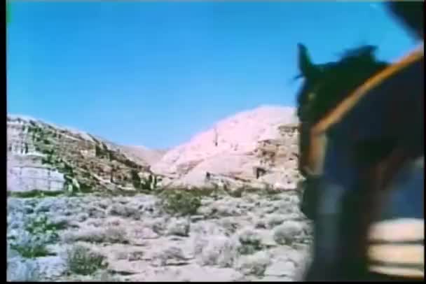 通过山地形疾驰的马背上骑兵军官和囚犯的后视图 — 图库视频影像