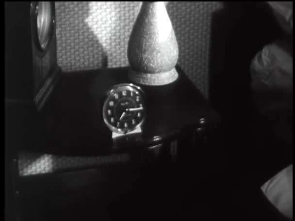 目覚まし時計を見るために手を差し伸べる女性 1960年代 — ストック動画