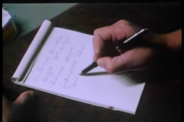 男子坐在桌前慢慢地写在纸上 — 图库视频影像
