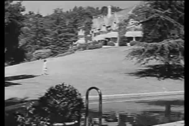 マンションに向かって芝生を横切って走っている女性のワイド ショット — ストック動画