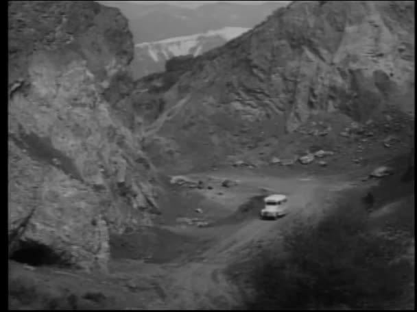 1950年代 山岳地帯で人々を解放するために停止するスクールバスの高角度ビュー — ストック動画