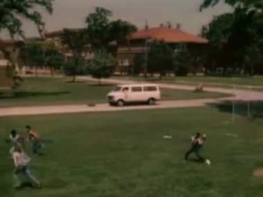 1980'lerde çimenlikte, futbol oynayan gençlerin geniş çekim