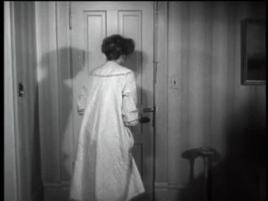 Korkmuş bir kadının 1960 'larda yatak odasının kapısını hızla kapatması.