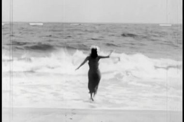 Okyanusa giren bir kadının arka görüntüsü.