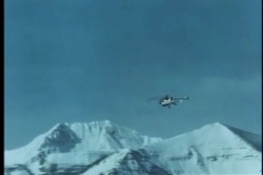 yüksek kar maskeli Dağların üzerinden uçan helikopter