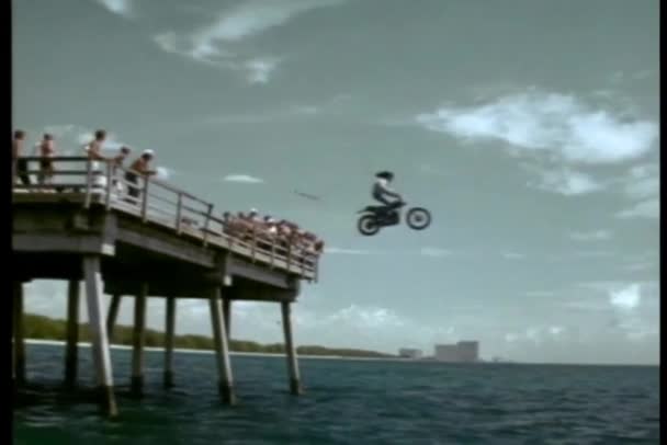 Stuntman Conduciendo Motocicleta Desde Muelle Hacia Océano — Vídeo de stock