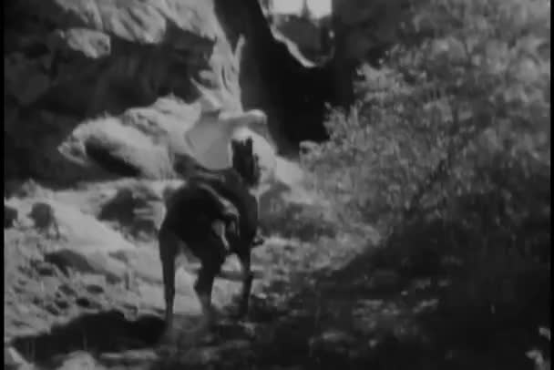 男子骑着马通过岩石地形舞动的后视图 图库视频
