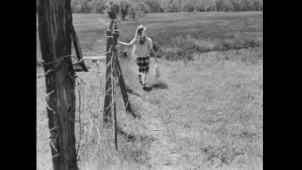 1940 フィールド フェンスで歩いている若い女性の後姿 — ストック動画