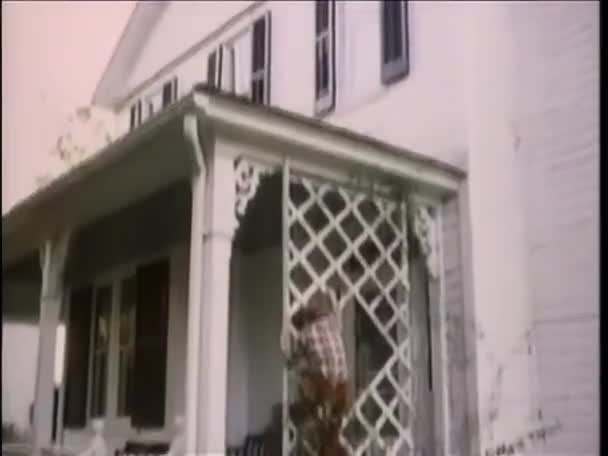 男の子は家の側に格子を登る — ストック動画