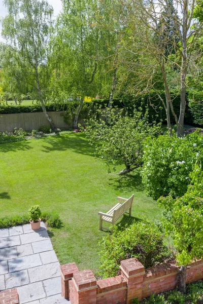 Wooden garden bench on lawn in a large luxury UK garden in spring