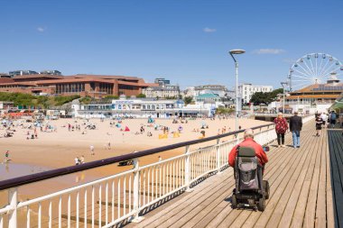 BOURNEMOUTH, UK - July 08, 2022. Elderly man on a mobility scooter on the promenade of Bournemouth Pier, Dorset, UK. Old age and disability