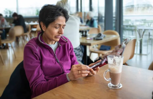 中年妇女独自坐在咖啡店的咖啡店里 使用手机 英国牛津 — 图库照片
