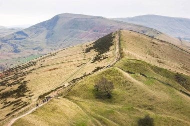 PEAK DISTRICT, İngiltere - 02 Mart 2023. Yürüyüşçüler Hollins Kavşağı 'na tırmanıyor. Uzakta annem Tor var. Peak District, Derbyshire, İngiltere