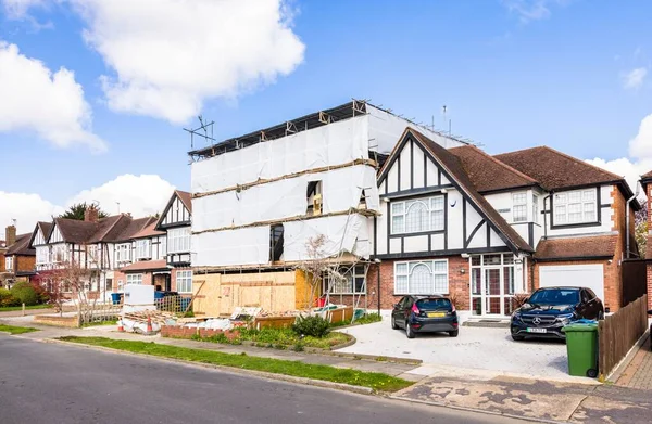 stock image LONDON, UK - April 11, 2023. House renovation, semi-detached suburban home covered with scaffold sheeting. 