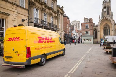 YORK, İngiltere - 19 Nisan 2023. Sarı DHL dağıtım aracı, şehir merkezinden geçen kurye..