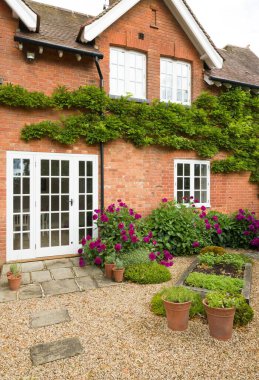 Verandalı ve Fransız kapılı İngiliz evi ve bahçesi. Kır evi ya da avlu bahçesi (arka bahçe) çakıllı ve York taş kaldırımlı
