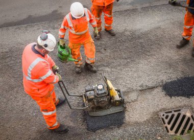 BUCKINGHAMSHIRE, İngiltere - 19 Mart 2024. Yol işçileri çukurları onarıyor. Onarımsız bir köy yolunda geçici çukur yaması onarımı.