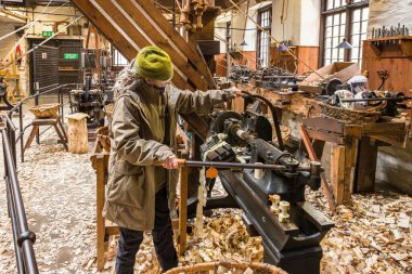 CumMBRIA, İngiltere - 25 Nisan 2024. İngiltere, Lake District 'teki Stott Park Bobbin Mill Müzesi' nde makine gösterisi yapan bir kadın.