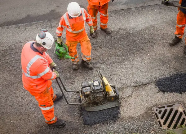 BUCKINGHAMSHIRE, İngiltere - 19 Mart 2024. Yol işçileri çukurları onarıyor. Onarımsız bir köy yolunda geçici çukur yaması onarımı.