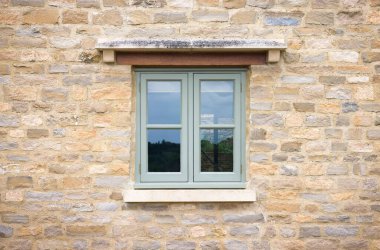 İngiltere 'de Cotswold taşından bir kulübenin yeşil boyalı ahşap penceresi.