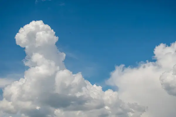 Kabarık beyaz kümülüs bulutları çerçeveye saçılmış berrak mavi bir gökyüzü. Bulutlar yoğun ve iyi tanımlanmış. Yumuşak, pamuk gibi bir doku oluşturuyor..