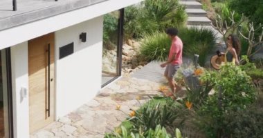 Güneşli tatil evinin kapısına bavullarıyla gelen mutlu çiftin videosu. Tatil, seyahat, birliktelik, rahatlama ve kapsayıcılık kavramı.