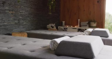 Sağlık merkezindeki masaj odasının dikey videosu. Masaj masaları, havlular ve mumlar. Tatil, birliktelik, rahatlama, sağlık, mutluluk ve kapsayıcılık kavramı.
