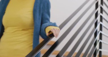 Evinin merdivenlerinde kameraya gülümseyen mutlu Asyalı bir kadının video portresi. Ev hayatı, sağlık, mutluluk ve kapsayıcılık kavramı.