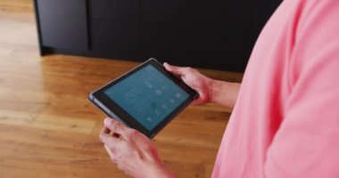 Melez bir adamın havayı kontrol ettiği tablet, gülümsediği ve tatil evinde etrafa bakındığı bir video. Tatil, seyahat, mutluluk, rahatlama ve kapsayıcılık kavramı.