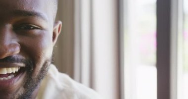 Evinde fotokopi çekerek gülümseyen Afro-Amerikan bir adamın yüzünün yarısının video portresi. Ev hayatı, sağlık, mutluluk ve kapsayıcılık kavramı.
