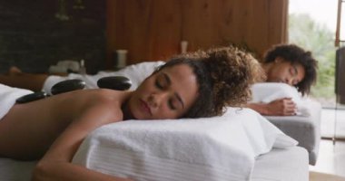 Rahatlamış bir çiftin sağlık merkezindeki sıcak taş masajının videosu. Tatil, birliktelik, rahatlama, sağlık, mutluluk ve kapsayıcılık kavramı.