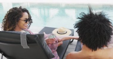 Mutlu çiftin içki içip dinlendiği ve tatil evinde havuz başında konuştuğu bir video. Tatil, birliktelik, rahatlama ve kapsayıcılık kavramı.