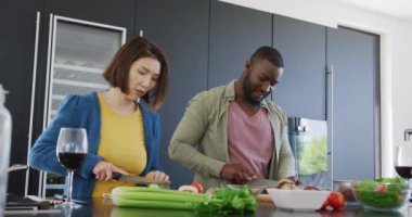 Mutfakta yemek hazırlayan ve birbirlerine gülümseyen mutlu çiftin videosu. Ev hayatı, aşk, sağlık, mutluluk ve kapsayıcılık kavramı.