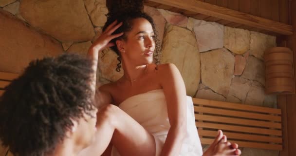 不同类型的夫妻穿着毛巾在桑拿的疗养室休息和聊天的视频 健康和包容性概念 — 图库视频影像