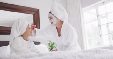 Mutlu Asyalı anne ve kızının yüzlerini nemlendirip eğlendiği bir video. Aile, annelik, ilişkiler ve birlikte kaliteli zaman geçirme konsepti dijital olarak oluşturulmuş video.