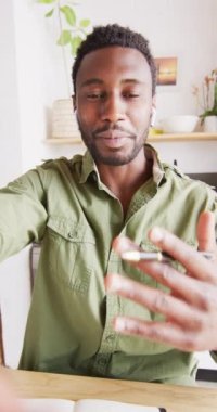 Mutfaktaki masada oturan mutlu Afro-Amerikan bir adamın video görüntüsü. Evde yalnız zaman geçirmek..