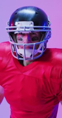 Kafkas erkek Amerikan futbolcusunun kask taktığı, neon ışıklı dikey video. Spor, hareket, eğitim ve aktif yaşam tarzı kavramı.